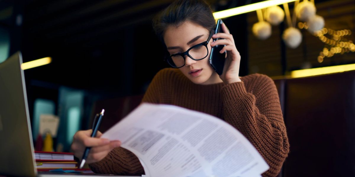 Woman on the phone reviewing paperwork